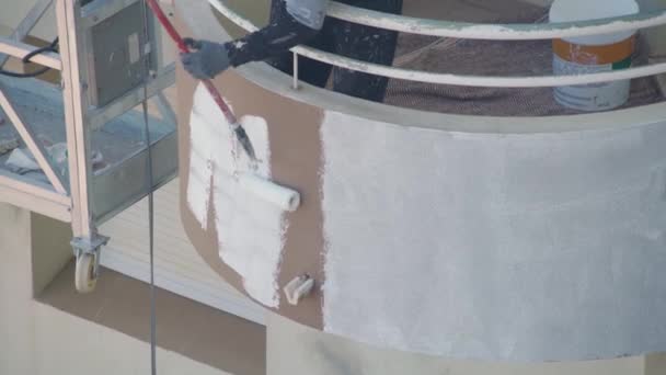 En professionell målare på en hiss målar väggarna i en flervåningshus vit. — Stockvideo