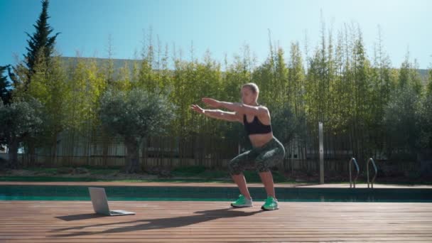 Young athletic fitness woman near swimming pool on online fitness class with personal trainer during pandemic. — Vídeo de Stock