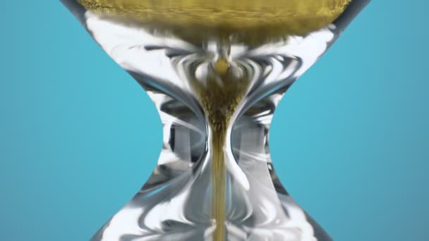 An hourglass made of yellow metal shavings passes through a funnel, symbolizing the concept of time in motion. Macro — Αρχείο Βίντεο