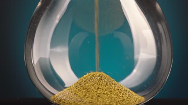Sárga fémforgácsból készült homokóra halad át egy tölcséren, ami a mozgásban lévő idő fogalmát szimbolizálja.. — Stock videók