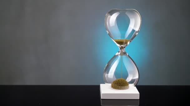 Un reloj de arena hecho de virutas de metal amarillo pasa a través de un embudo, simbolizando el concepto de tiempo en movimiento. — Vídeo de stock