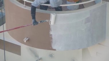 Asansördeki profesyonel bir ressam çok katlı bir binanın duvarlarını beyaza boyar..