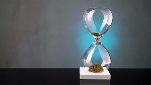 Ett timglas gjort av gula metallspån passerar genom en tratt, symboliserar begreppet tid i rörelse. — Stockvideo