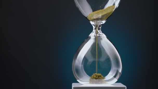 Пісочний годинник з жовтої металевої стружки проходить через воронку, символізуючи концепцію часу в русі . — стокове відео