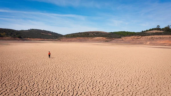 在干旱期间,一个人在沙地上的轮廓在空旷而贫瘠的土地上出现了裂缝.地球上的生态灾难概念. — 图库照片