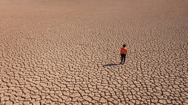 Silhouette d'un homme sur une terre sablonneuse fissurée vide pas fertile lors d'une sécheresse. Le concept de catastrophe écologique sur la planète. — Photo