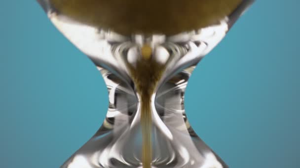 An hourglass made of yellow metal shavings passes through a funnel, symbolizing the concept of time in motion. — Αρχείο Βίντεο