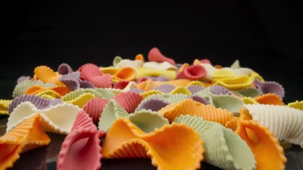 Pasta multicolor creativa farfalle sobre un fondo negro en perspectiva de fondo. Movimiento macro extrema — Vídeos de Stock