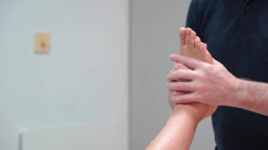 Bir ortopedik osteopat, bir yaralanmadan sonra bacağı yerine koymak için masaj manipülasyonları yapar. Kadın bacağının fizyoterapisi. Yakın plan..