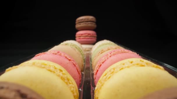 Gekleurde macarons zoetwaren marshmallows op een zwarte reflecterende achtergrond in perspectief. Extreme kant macro. — Stockvideo