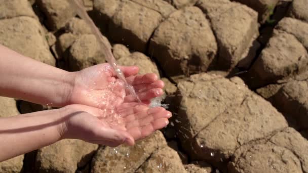 Концепция экологической катастрофы засухи и недостатка пресной воды в мире. Чистая вода течет в руке на фоне песчаной трещины земли. — стоковое видео