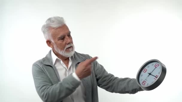 Porträt eines älteren kaukasischen stilvollen Mannes zeigt auf das Uhrkonzept Zeit ist Geld. Im Atelier auf weißem Hintergrund. Konzept der Trendalterung. — Stockvideo