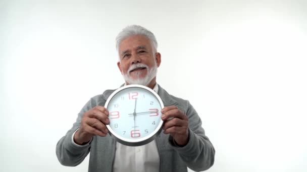 Πορτρέτο ενός ηλικιωμένου καυκάσιος κομψός άνθρωπος δείχνει προς το ρολόι έννοια του χρόνου είναι τα χρήματα. Στο στούντιο σε λευκό φόντο. Έννοια της γήρανσης τάση. — Αρχείο Βίντεο