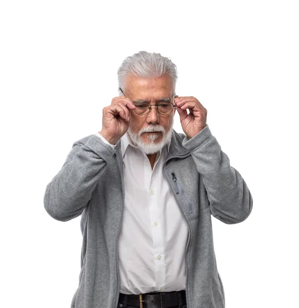 En äldre stilren man i glasögon med skägg och grått hår tittar åt sidan och håller i glasögon med händerna. På en vit isolerad bakgrund. — Stockfoto