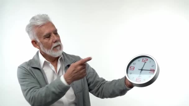 노인의 노인의 초상화는 시계 개념 이 돈이라는 것을 지적한다. 하얀 배경의 스튜디오에서요. 유행 노화에 대한 개념. — 비디오