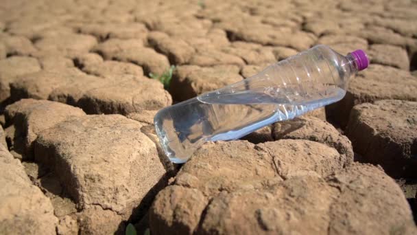 Botella con agua dulce limpia en arena en el desierto durante la sequía concepto de desastre ambiental. Calentamiento global. — Vídeo de stock