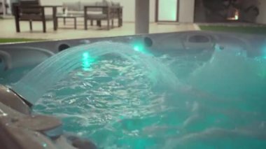 Modern bir jakuzinin yüzeyine yakın çekim. Rahatlama terapisi ve bir otelde rehabilitasyon için. Oksijen basıncı altında küvette su kabarcıkları Akşam vakti dışarıda ışıklarla