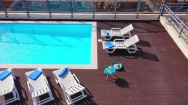 Evin çatısında turistlerin berrak mavi suyla dinlenmeleri için güneş pansiyonları ve havlular olan lüks bir havuz var. Geleceğin altyapı lüks konsepti.