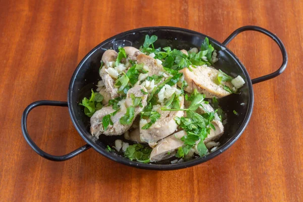 Mediterraan gerecht voorgerecht van gekookte kabeljauwkuit gemarineerd in olijfolie en peterselie. In een steelpan op een houten achtergrond. — Stockfoto