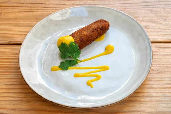 Aperitivo croquete frito regado com molho de mostarda, aperitivo mediterrâneo. Em uma chapa em um fundo de madeira close-up. — Fotografia de Stock