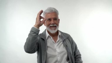 Gri sakallı ve saçlı şık yaşlı adam, beyaz izole bir arka planda her şeyin yolunda olduğunu gösteriyor. Emeklilik modası karakteri.