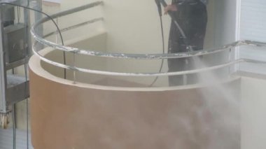 Bir adam çok katlı bir binanın duvarlarını dezenfekte etmek için yüksek basınçlı bir makine kullanıyor. Endüstriyel boya asansöründe.