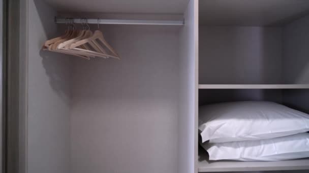 Armario empotrado en un hotel con estantes de almohadas y perchas para los turistas de cerca. — Vídeos de Stock