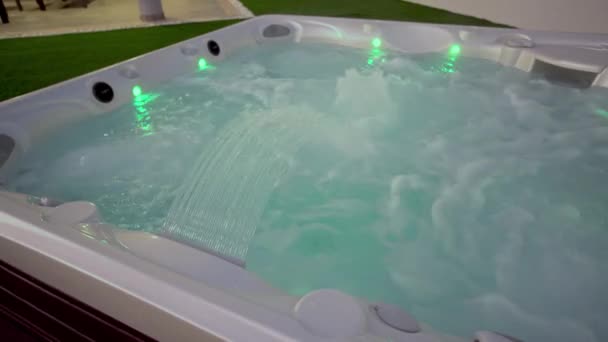 Nahaufnahme der Oberfläche eines modernen Whirlpools für Entspannungstherapie und Rehabilitation in einem Hotel. Wasserblasen in einem Bad unter Sauerstoffdruck Abends draußen mit Licht — Stockvideo