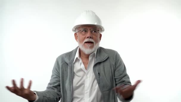 Пожилой пенсионер в строительном шлеме изображает инженера говорящего и жестикулирующего на белом фоне. — стоковое видео