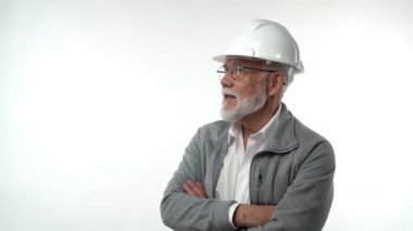 İnşaat kasklı yaşlı bir adam beyaz bir arka planda konuşan ve el kol hareketi yapan bir mühendisi resmediyor. Yüksek kaliteli FullHD görüntüler