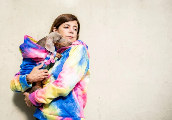Latin woman holding her dog both dressed alike.  They seem to be worried.  Grey background. Copy space