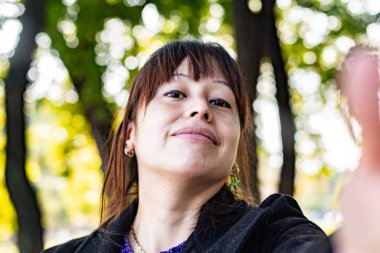 Genç bir kadın fotoğraf makinesinde gülümsüyor.