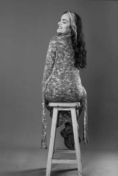 Rear view of woman sitting on chair. Studio Shot.