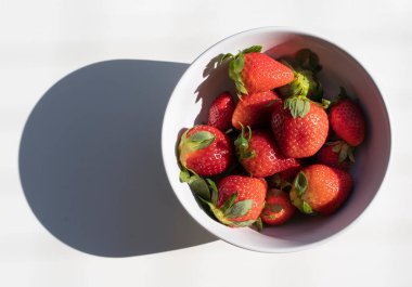 Top view of fresh strawberries in a white bowl isolated on white background