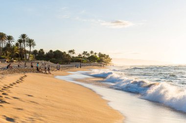Gün batımında Sunset Plajı 'ndaki insanlar. Sunset Beach, Oahu 'nun kuzey kıyısında yer alır ve adadaki günbatımını izlemek için en iyi yerdir.