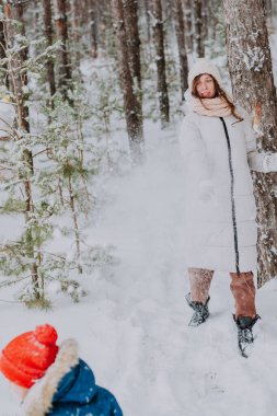mom and son play snowballs in the winter forest. Mom walks with her son in a snowfall in the forest. Happy winter holidays with snow. Winter walks in the forest.