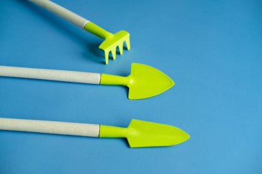 Parlak yeşil kürek ve tırmıkla mavi arka plan manzarası. Pankart. Baharatları kopyala. düz yat