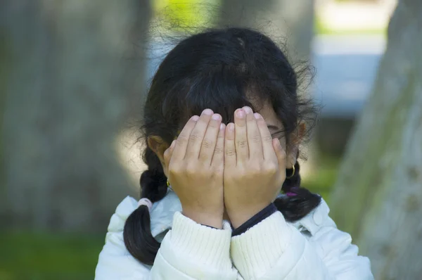 Klein meisje speelt verstoppertje verbergen gezicht — Stockfoto