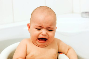 Ağlayan bebek banyo yapıyor. Bebek yıkanmak istemiyor.