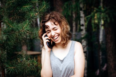 Güzel genç kız ormanda telefonla konuşuyor..