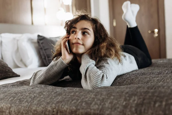 Szczęśliwy Uśmiechnięty Nastolatek Dziewczyna Mówi Przez Telefon Leżąc Jej Łóżku — Zdjęcie stockowe
