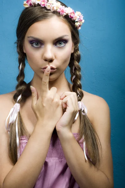 Young emotional woman with finger on lips