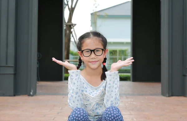 庭の屋外でパビリオンに座っている間 アジアの女の子の子供は開いて手とカメラを見て眼鏡をかけて — ストック写真