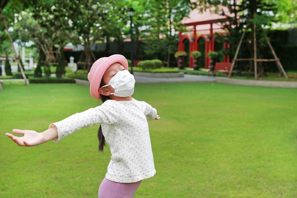 アジアの若いです女の子子供身に着けています医療マスクとともにオープンワイド腕原因Covid 19のためにザ庭 — ストック写真