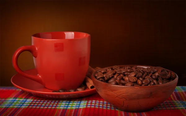 Taza de café y granos de café en un mantel sobre un fondo oscuro — Foto de Stock