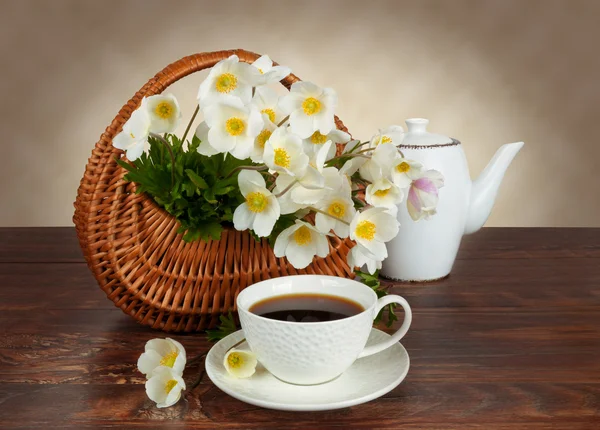 Buquê de flores em uma cesta e uma caneca de chá — Fotografia de Stock
