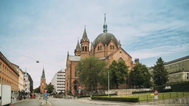 Oslo, Norveç. Trefoldighetskirken yakınlarında trafik - Akersgata Caddesi 'ndeki Kutsal Üçlemeci Kilisesi. Yaz günü. 4K