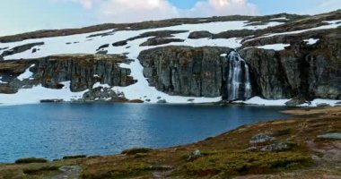Aurlandsfjellet, Norveç. Şelale ve Flotvatnet Gölü ilkbaharda karlı bir arazide. Yazın Norveç 'te Manzaralı Yol. Doğal Norveç Tarihi Yeri ve Popüler İstikamet
