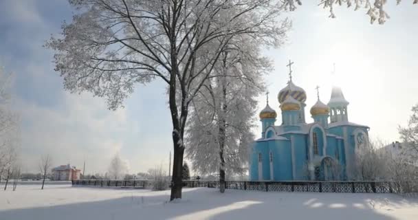 Dorf Krasnoe, Region Gomel, Weißrussland. Alte orthodoxe Kirche Mariä Himmelfahrt am sonnigen Winterschneetag. Berühmtes Wahrzeichen unter Schneefall im Snowy Park — Stockvideo