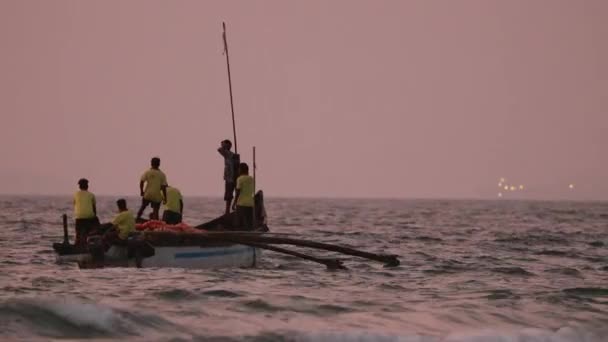 Goa, India - 10 de febrero de 2020: Pescadores en barco tirando de la red de pesca al atardecer — Vídeo de stock